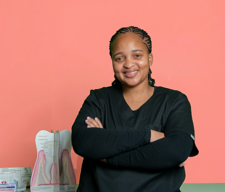 Tebogo Mongae, the dental secretary at Mahikeng Medical Center, smiling with arms crossed beside a dental model
